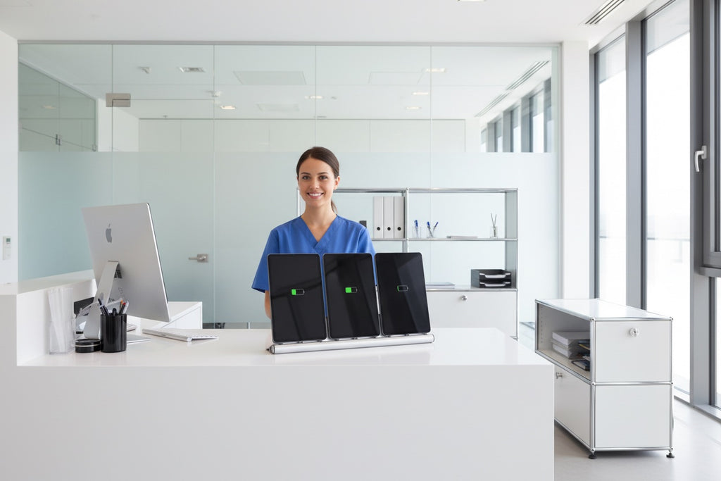 Person standing behind a counter with three laptops on a white surface in a modern office setting. AA